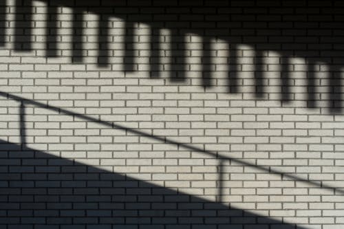 A shadow of a person walking on a brick wall