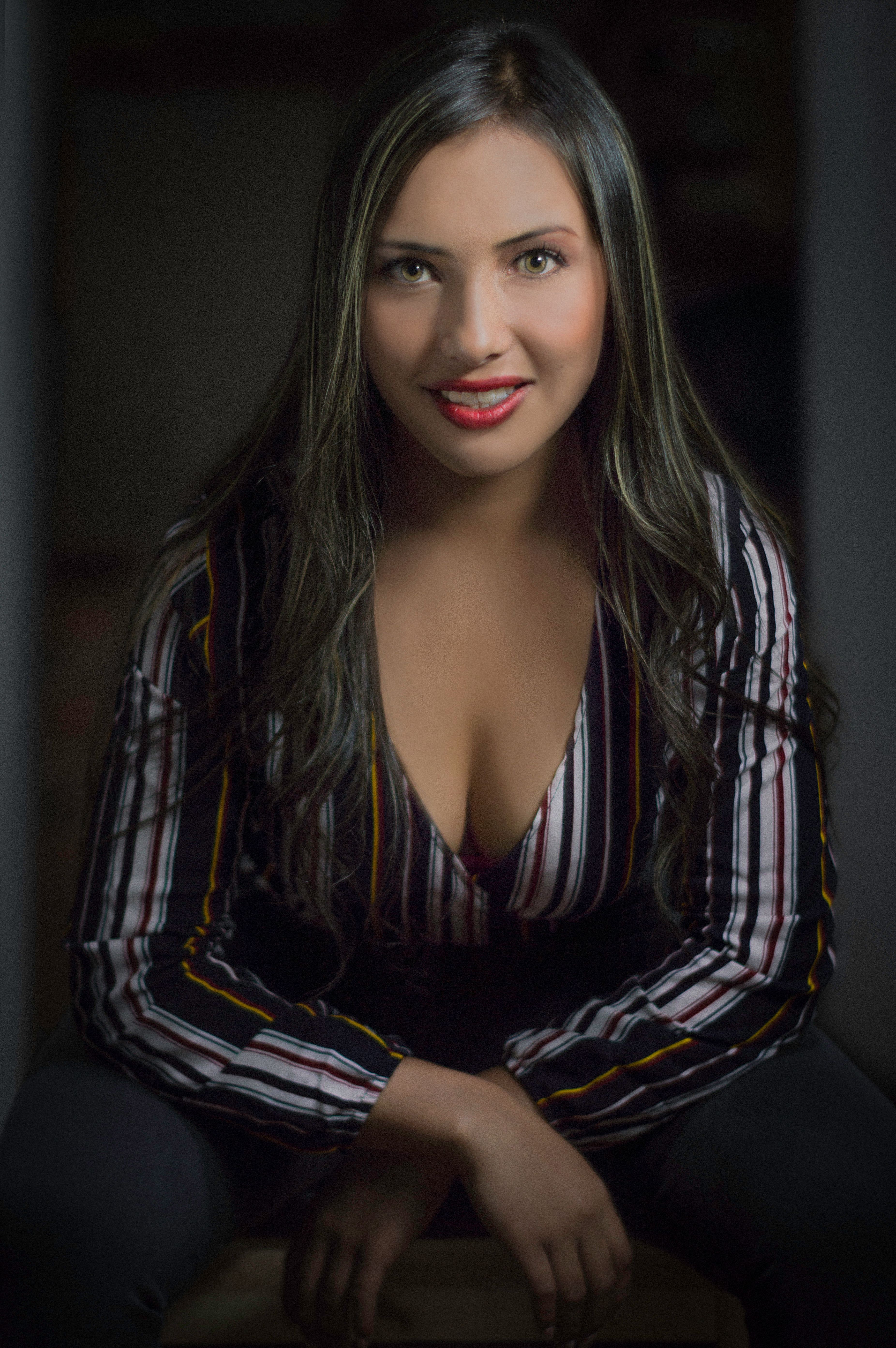 Confident woman with long hair and a smile, seated in a striped blouse. Perfect for fashion shoots.
