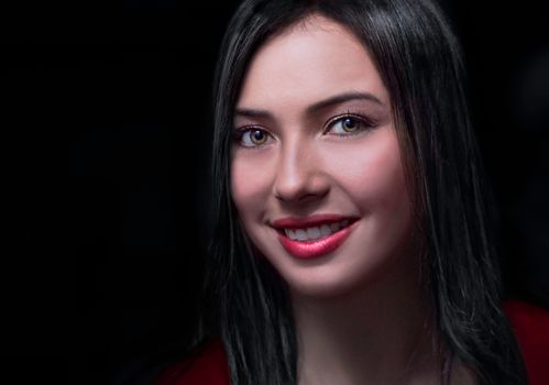 Portrait of a smiling brunette woman with a dark background, emphasizing her friendly expression.