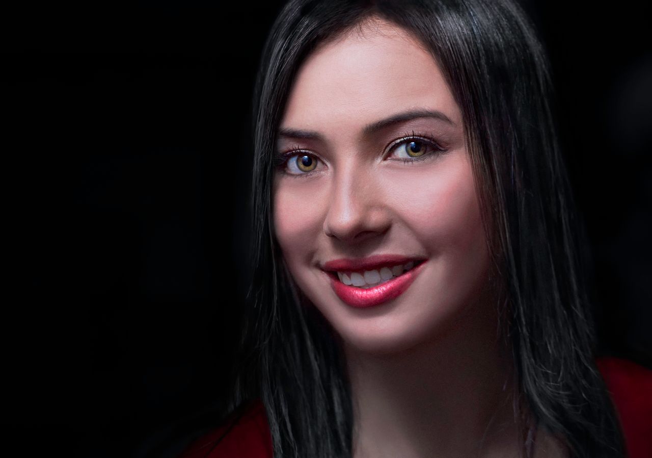 portrait of a smiling brunette woman with a dark background emphasizin