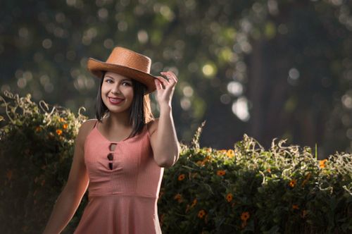 Free Smiling woman in a straw hat posing in a summer garden. Fashionable and cheerful vibe. Stock Photo
