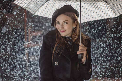 A woman in a black coat holding an umbrella