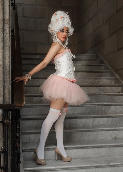 Free Woman in Rococo style attire posing on stone staircase indoors. Stock Photo