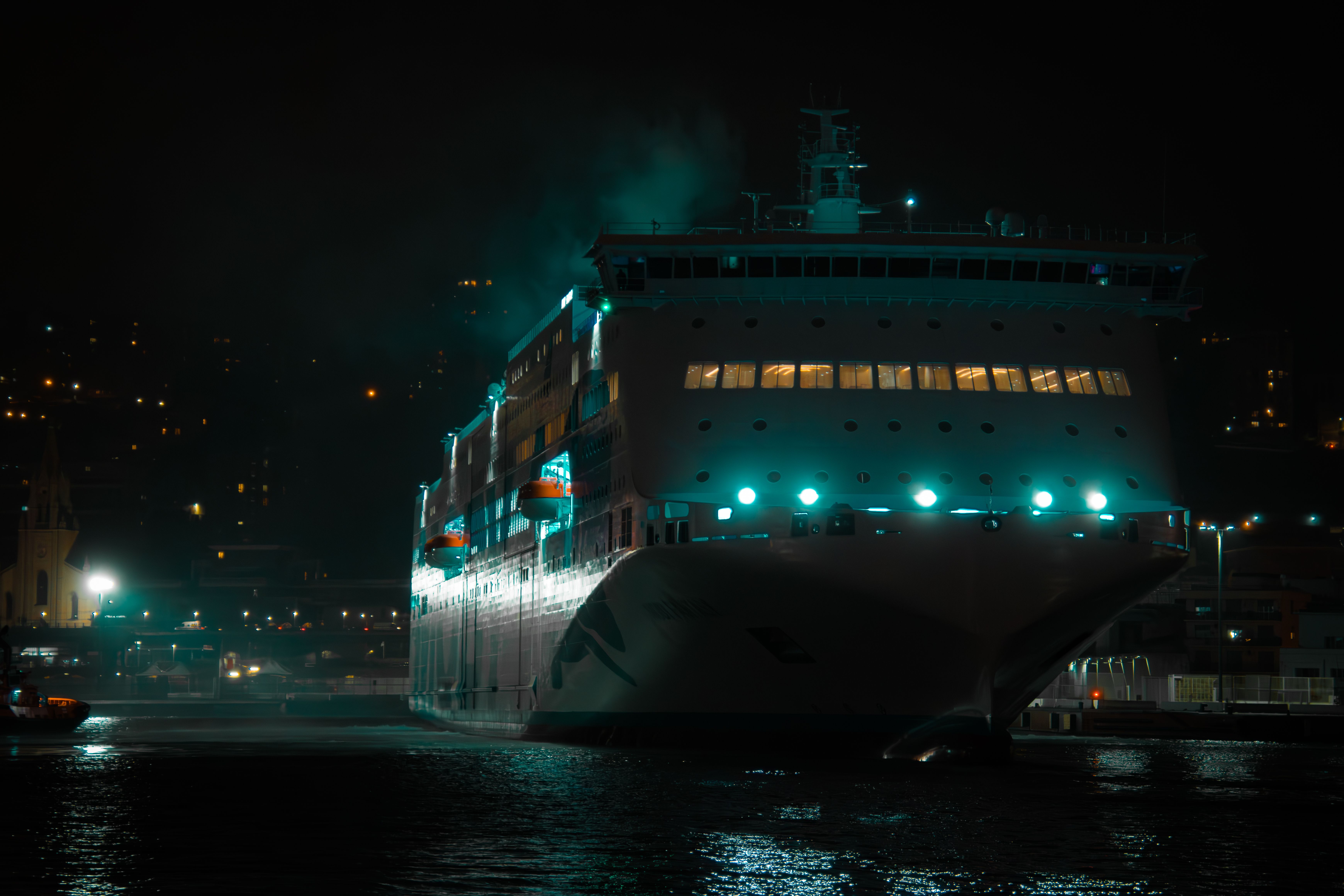 Illuminated cruise ship docked at Genoa's harbor, showcasing night-time elegance.