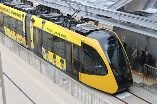 A yellow and black train is at the station