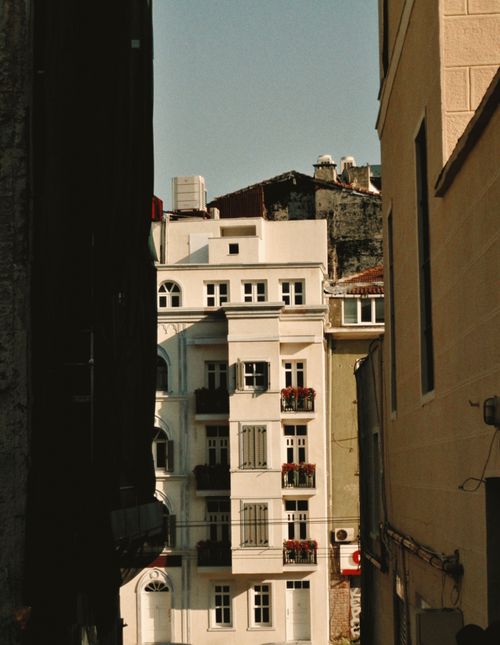 Free A picturesque urban apartment building with balconies framed between narrow city alleys. Stock Photo