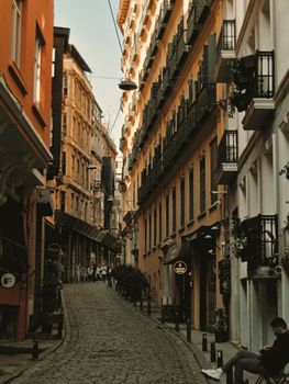 Charming cobblestone street with historic architecture in Istanbul, featuring a person sitting and warm evening tones.