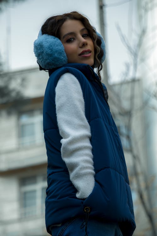 A woman wearing a blue vest and earmuffs