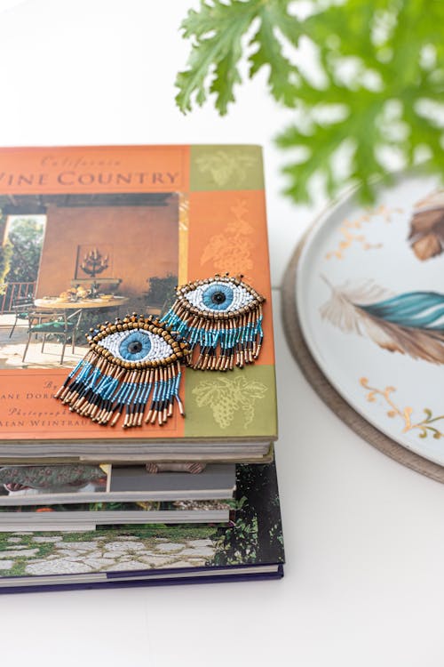 A pair of blue and turquoise earrings sitting on top of a book