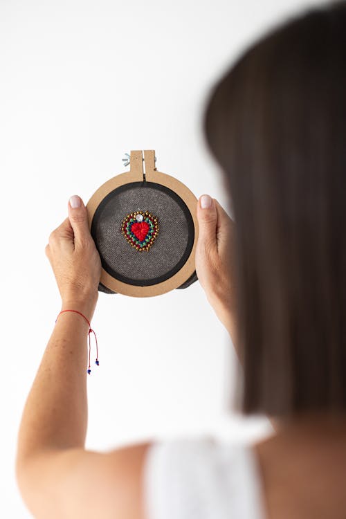A woman holding a cross stitch with a red heart