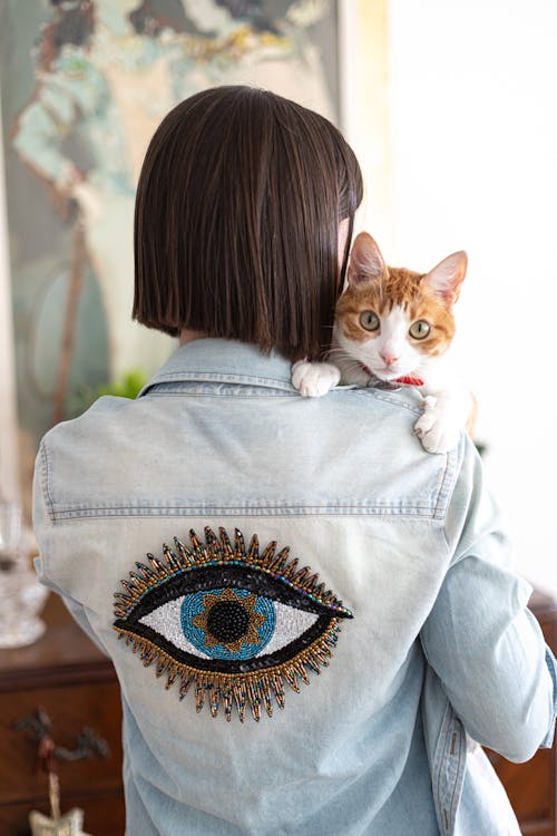 A woman holding a cat wearing an eye patch