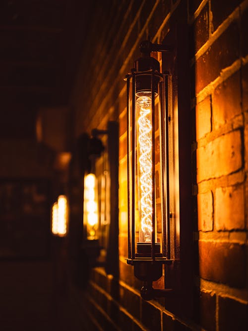 a low light photo of a vintage light that is hanging on a brick wall