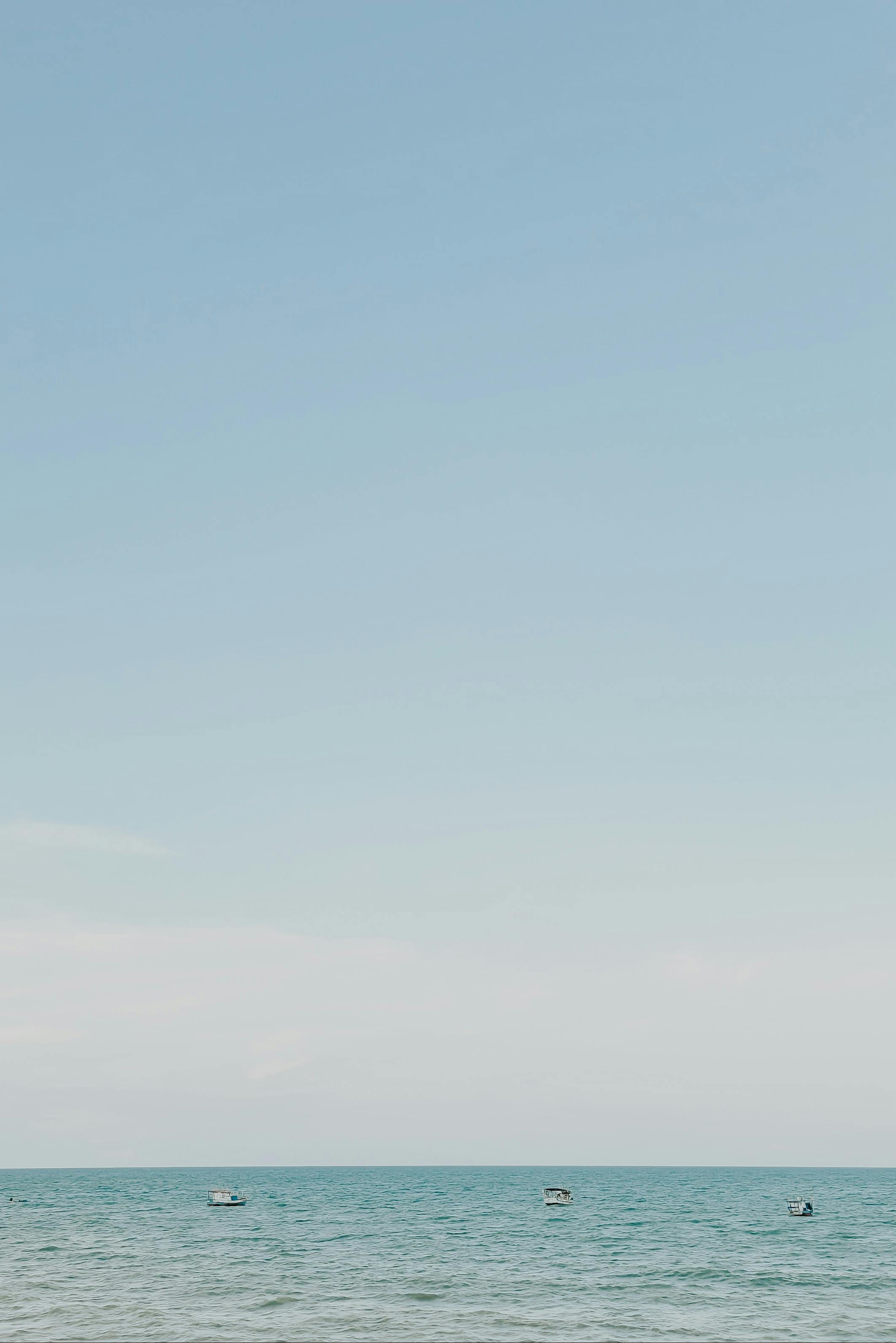 Tranquil view of the ocean and sky in Brazil with distant boats and clear blue sky.