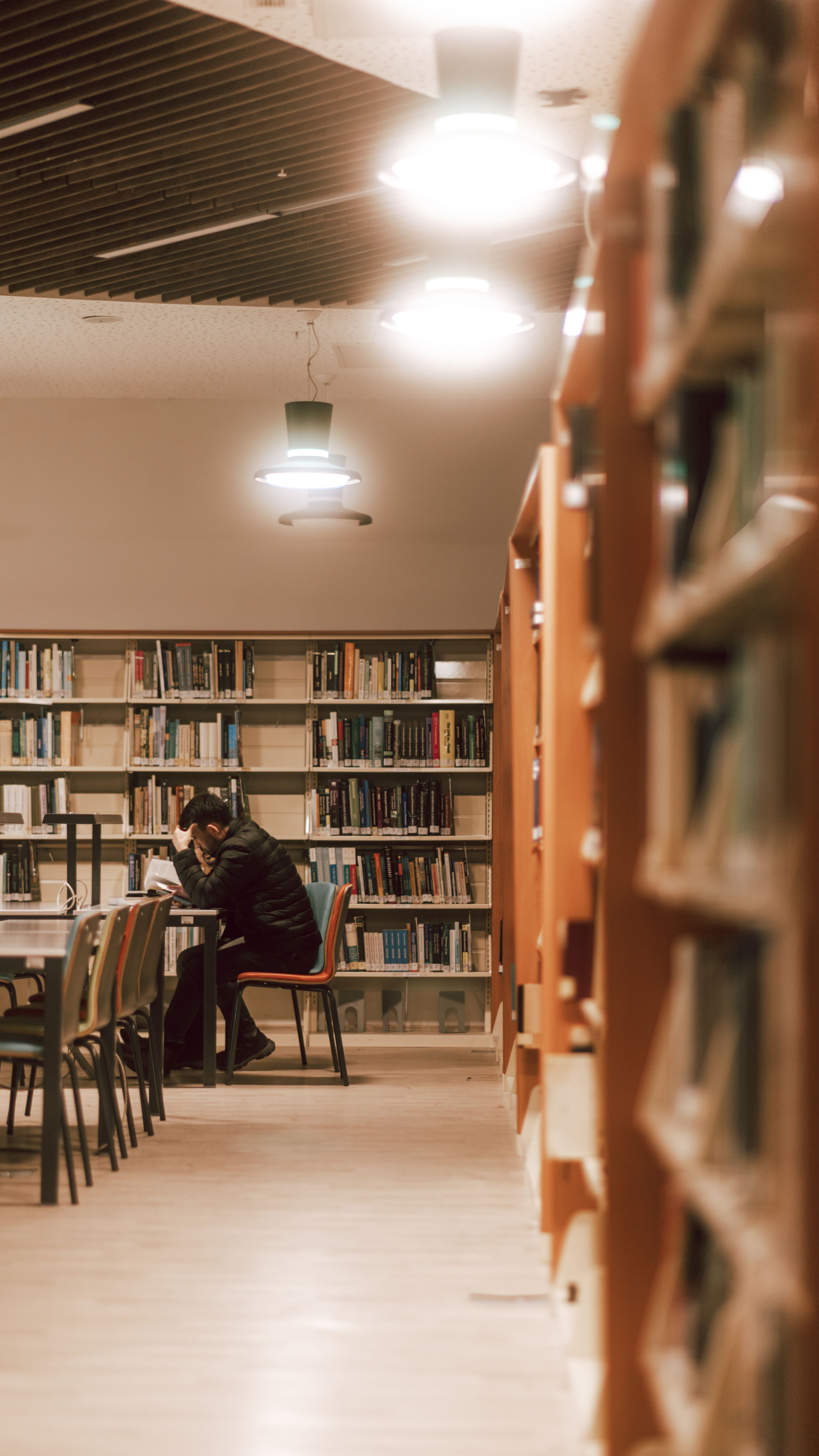 A person sitting at a table in a library · Free Stock Photo