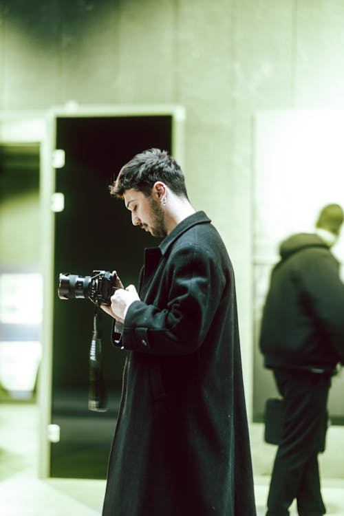 A man in a coat holding a camera