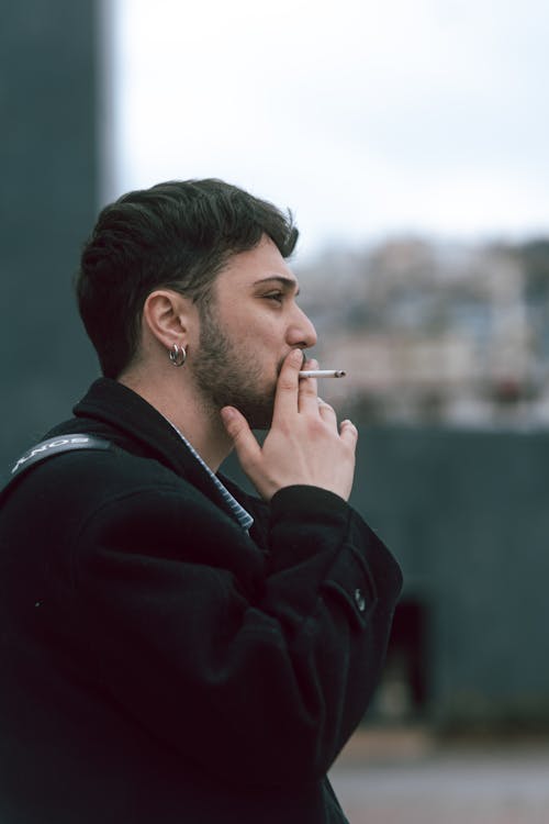 A man smoking a cigarette in front of a building