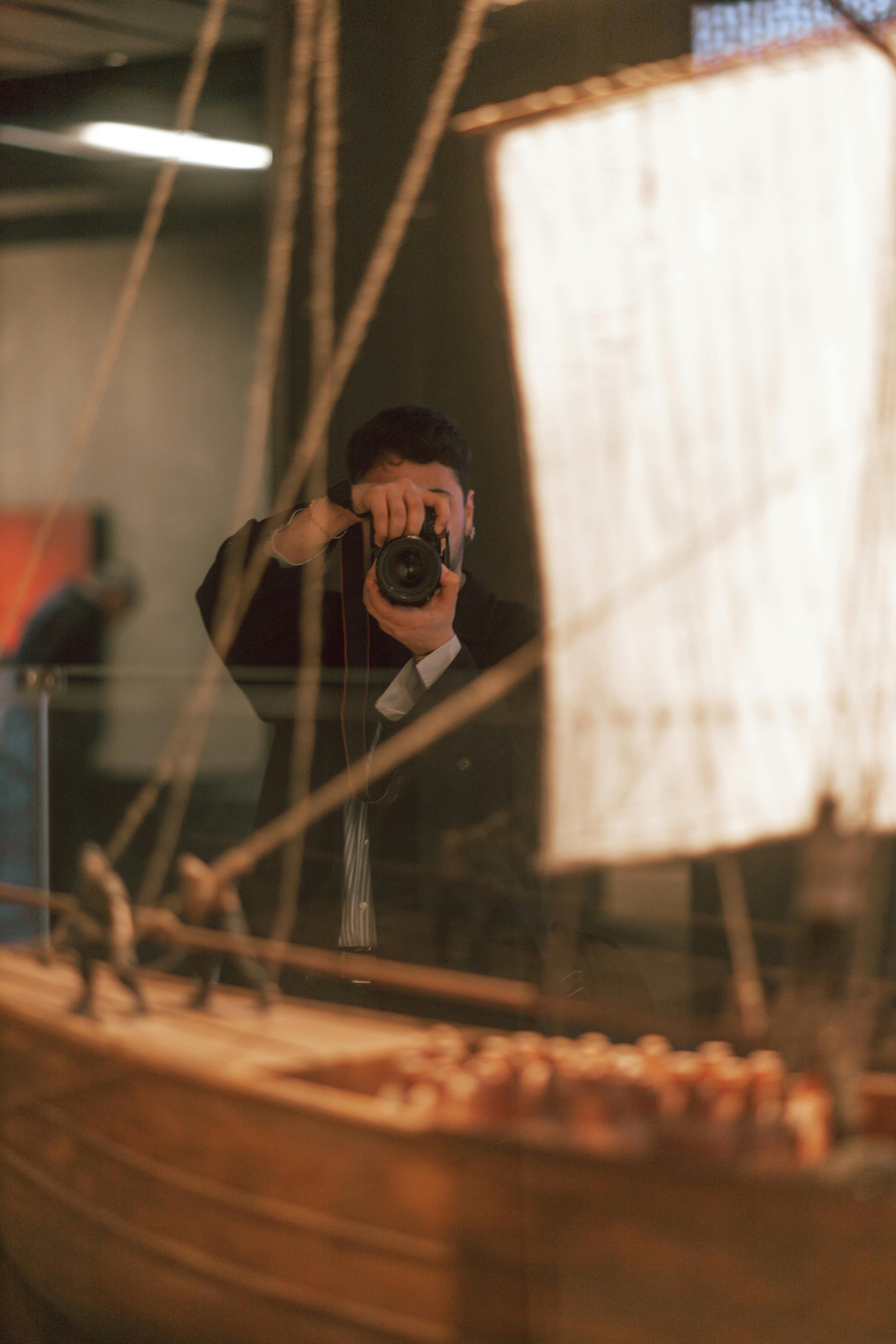 Free A photographer taking a picture of a miniature model ship displayed in a museum exhibit. Stock Photo