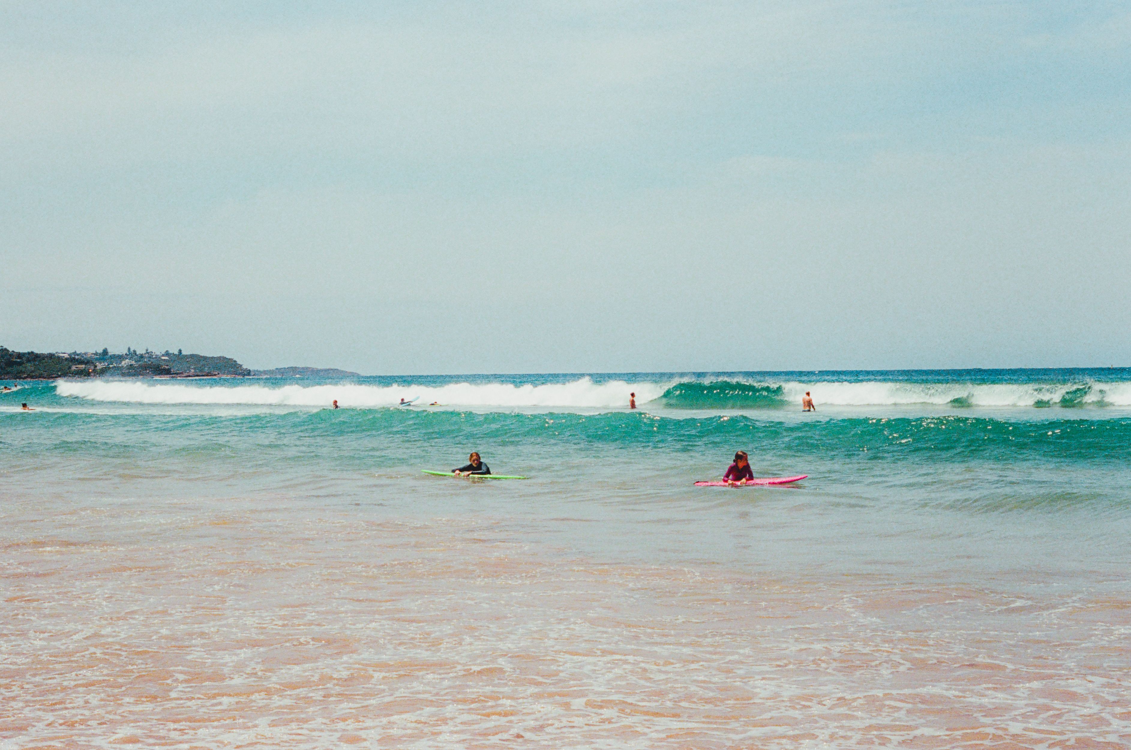 Surfers enjoying the waves at Manly Beach in Australia, capturing a perfect summer day.