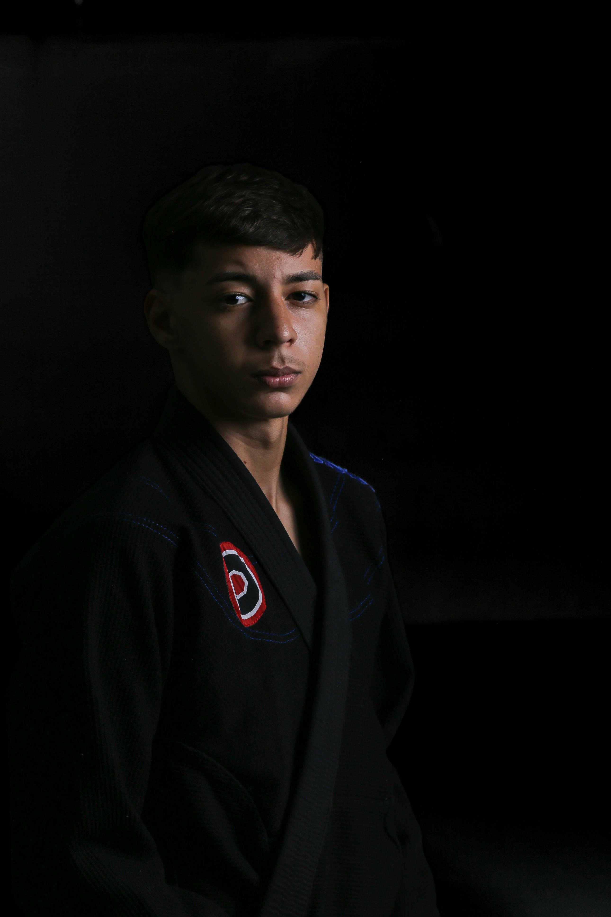 Studio portrait of a man in a black martial arts gi, exuding confidence and focus.