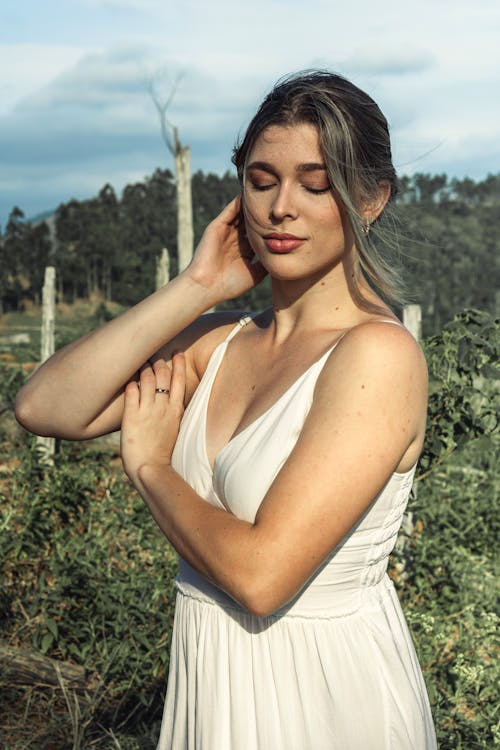 A woman in a white dress is standing in a field
