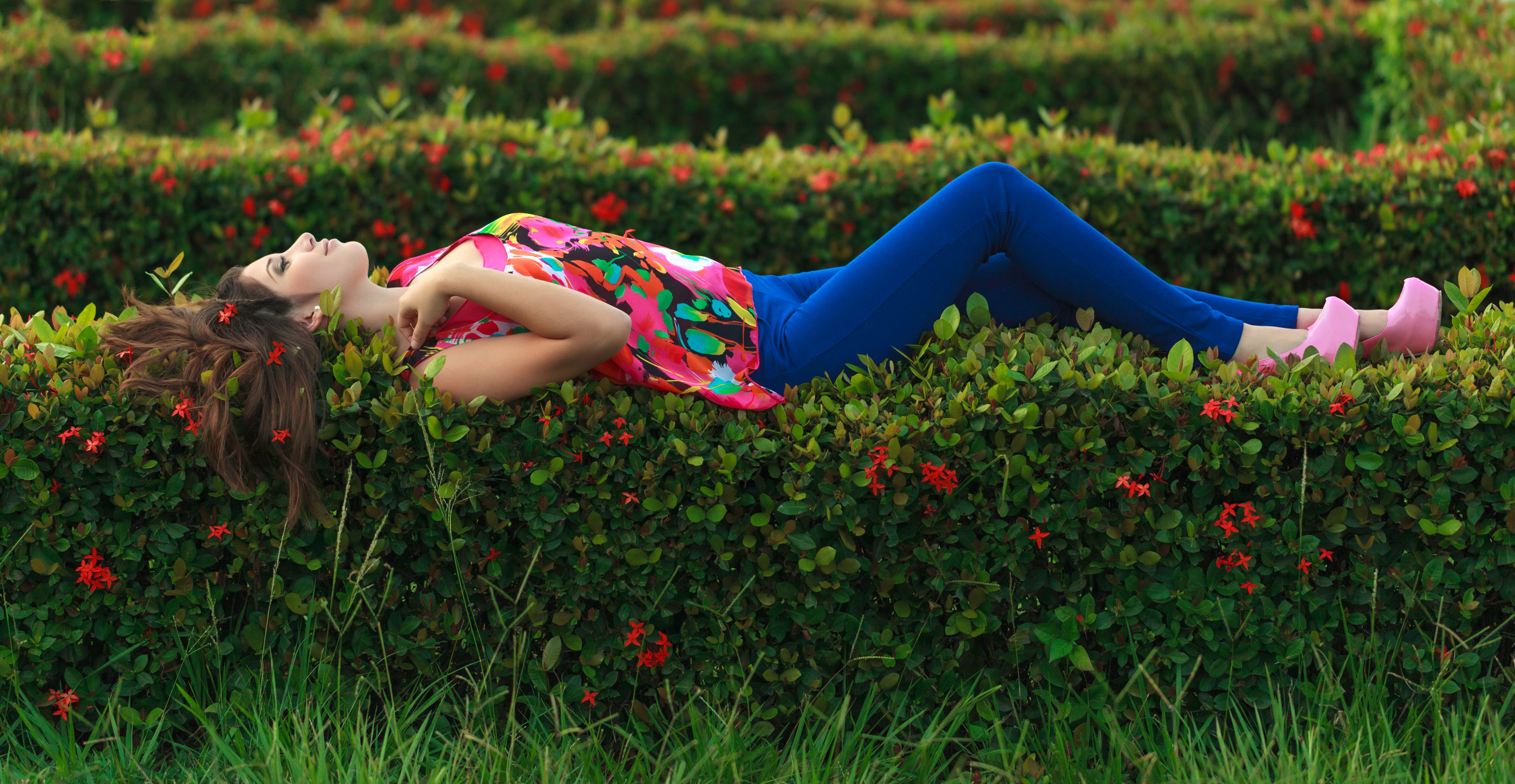 Colorful fashion portrait of a woman lying in a blossoming garden, showcasing vibrant style and relaxation.