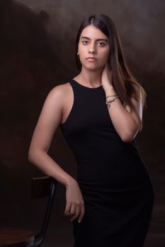 Stunning portrait of a young woman in a black dress posing in a studio setting.