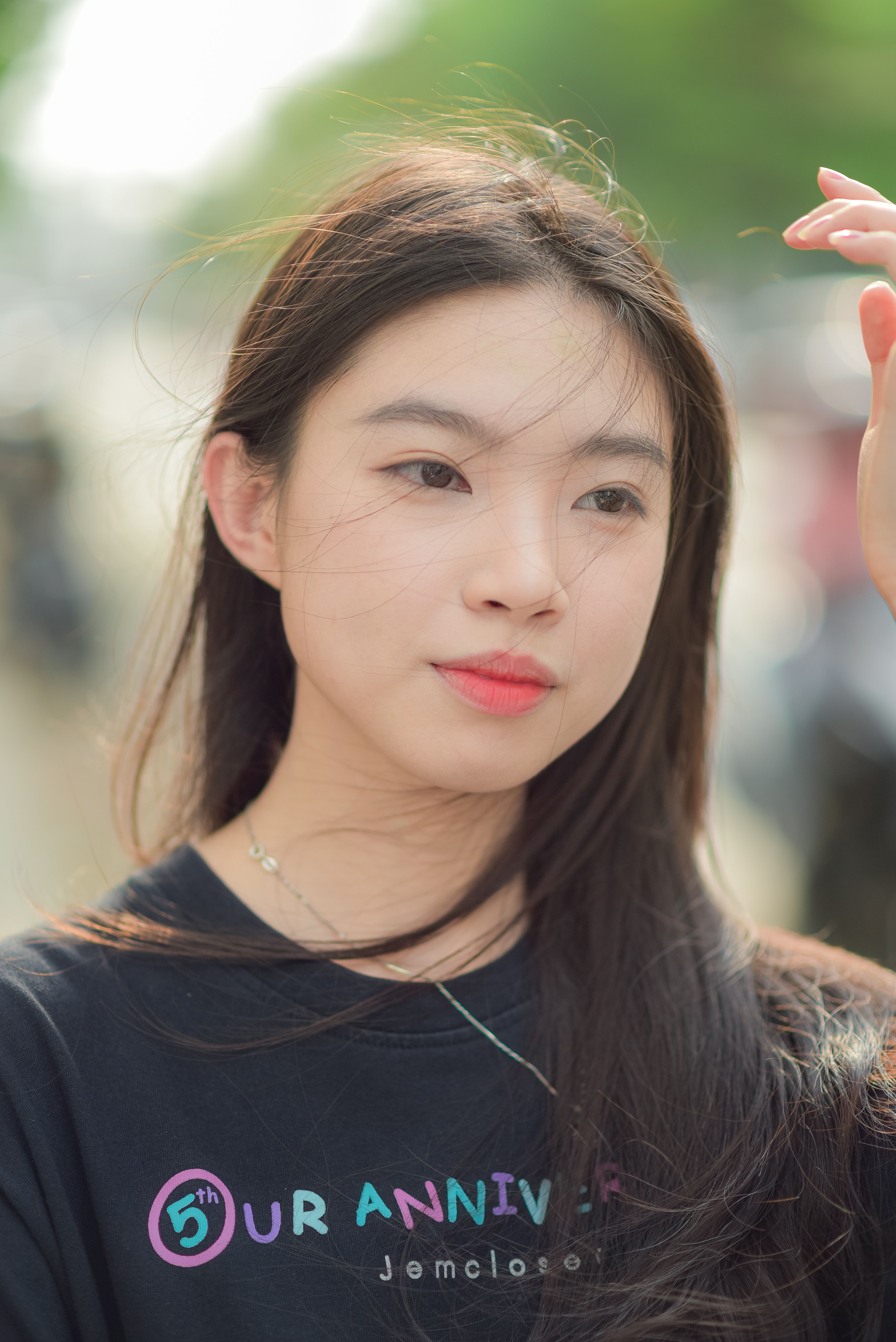 Close-up portrait of a young woman outdoors with wind in her hair.