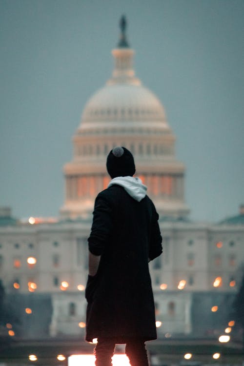 A man in a hoodie standing in front of the capitol building