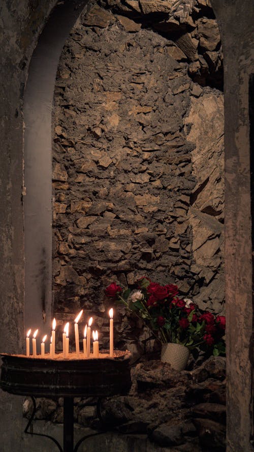 A candle lit in front of a stone wall