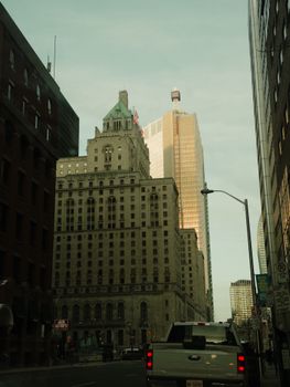 Iconic Fairmont Royal York hotel with Toronto city skyline and vehicles on street at dusk.