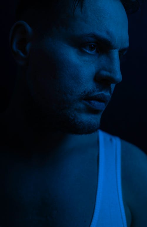A man in a tank top and blue light