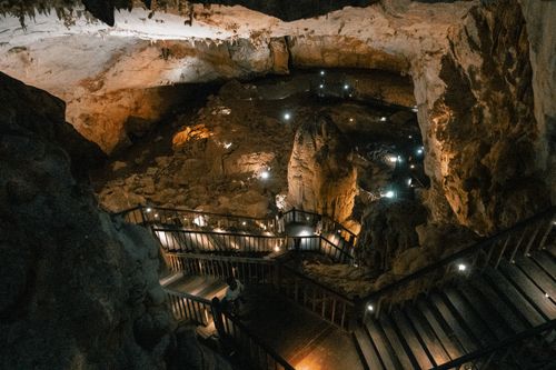 Free A stunning view of a cave with illuminated pathways and natural rock formations. Stock Photo