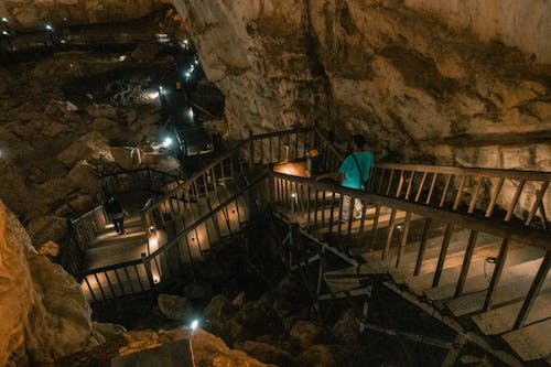 A man walking down a wooden staircase in a cave