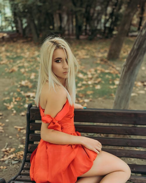 A blonde woman in red dress sitting on a bench