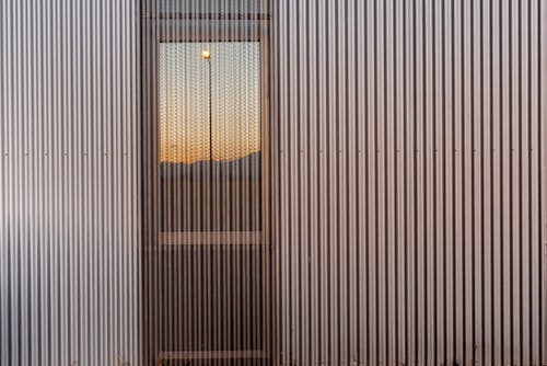 Metallic wall with a glass door reflecting the sunset