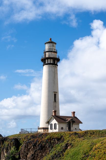 Pigeon Point Lighthouse stands tall against a bright blue sky in Pescadero, California.
