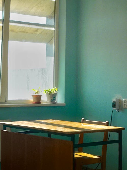 A table and chair in a room with a window