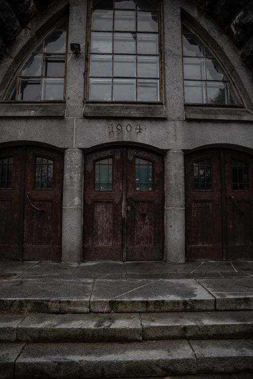 Free Vintage wooden doors on a stone building with arched windows, dated 1904. Stock Photo