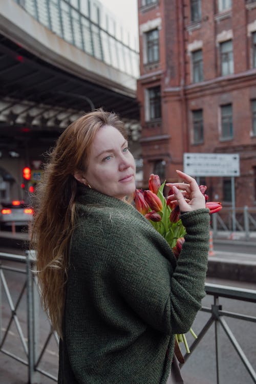 A woman holding a bouquet of flowers in front of a bridge