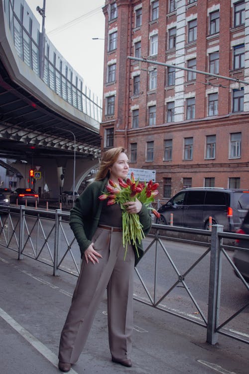 A woman standing on a bridge holding flowers