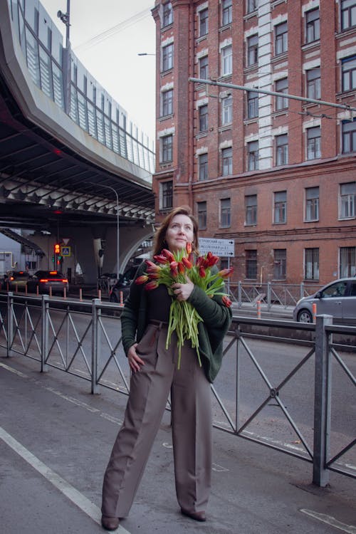A woman holding a bouquet of flowers on a bridge