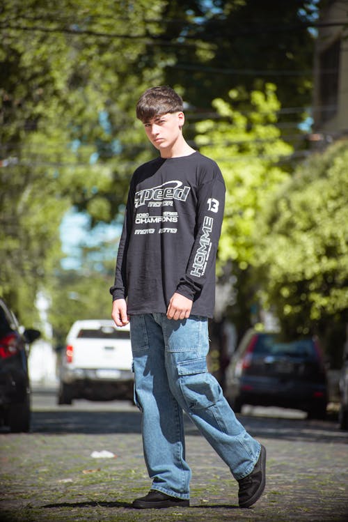 A young man in jeans and a black shirt standing on a street