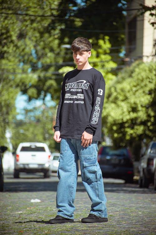 A man standing on a street wearing jeans and a black shirt