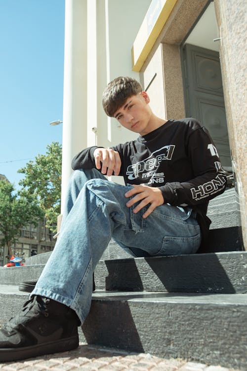 A young man sitting on the steps of a building