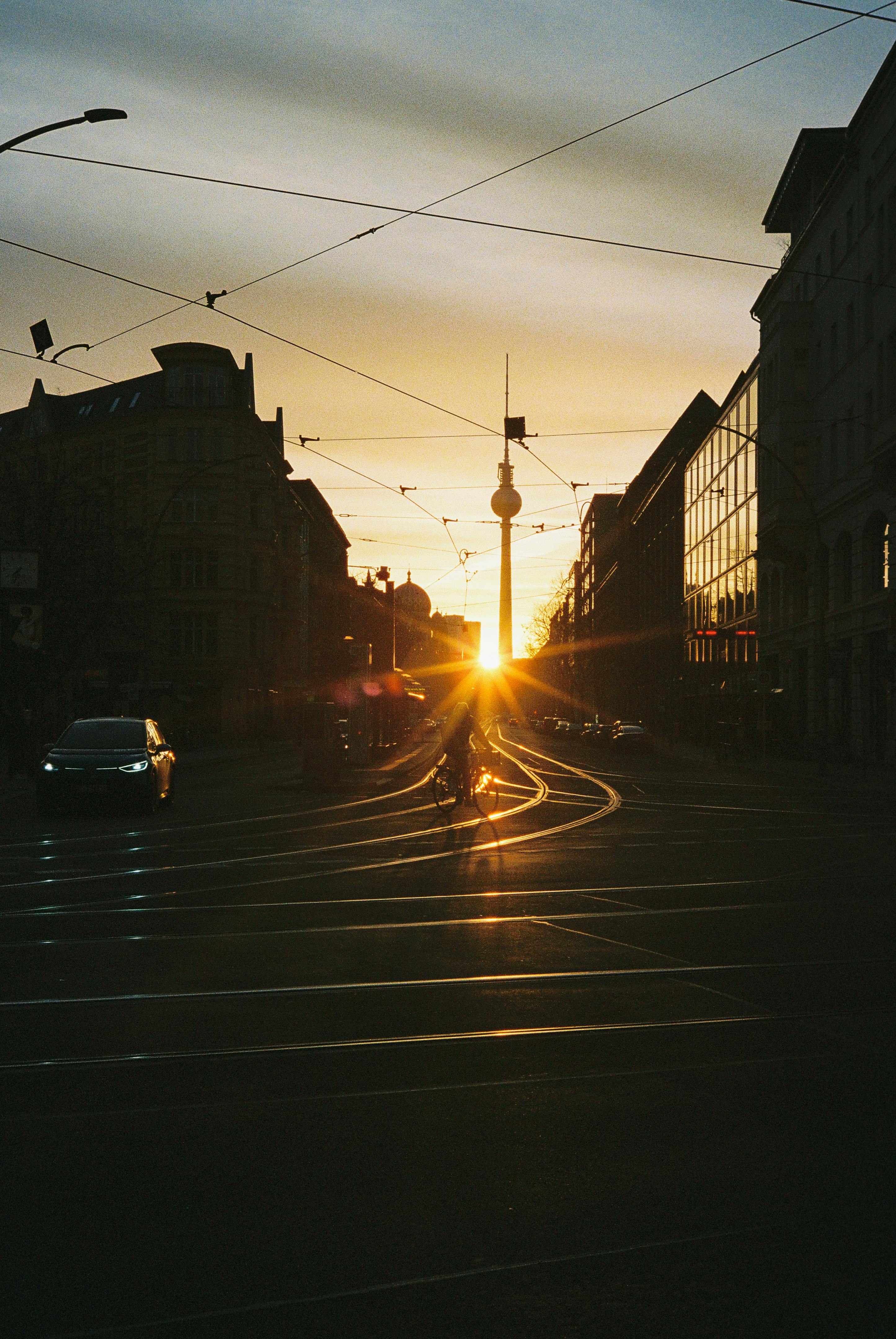 Dramatic sunrise over urban streets in Berlin, featuring iconic TV Tower against a cityscape.