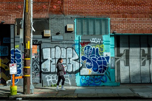 A woman walking down the street past graffiti covered buildings
