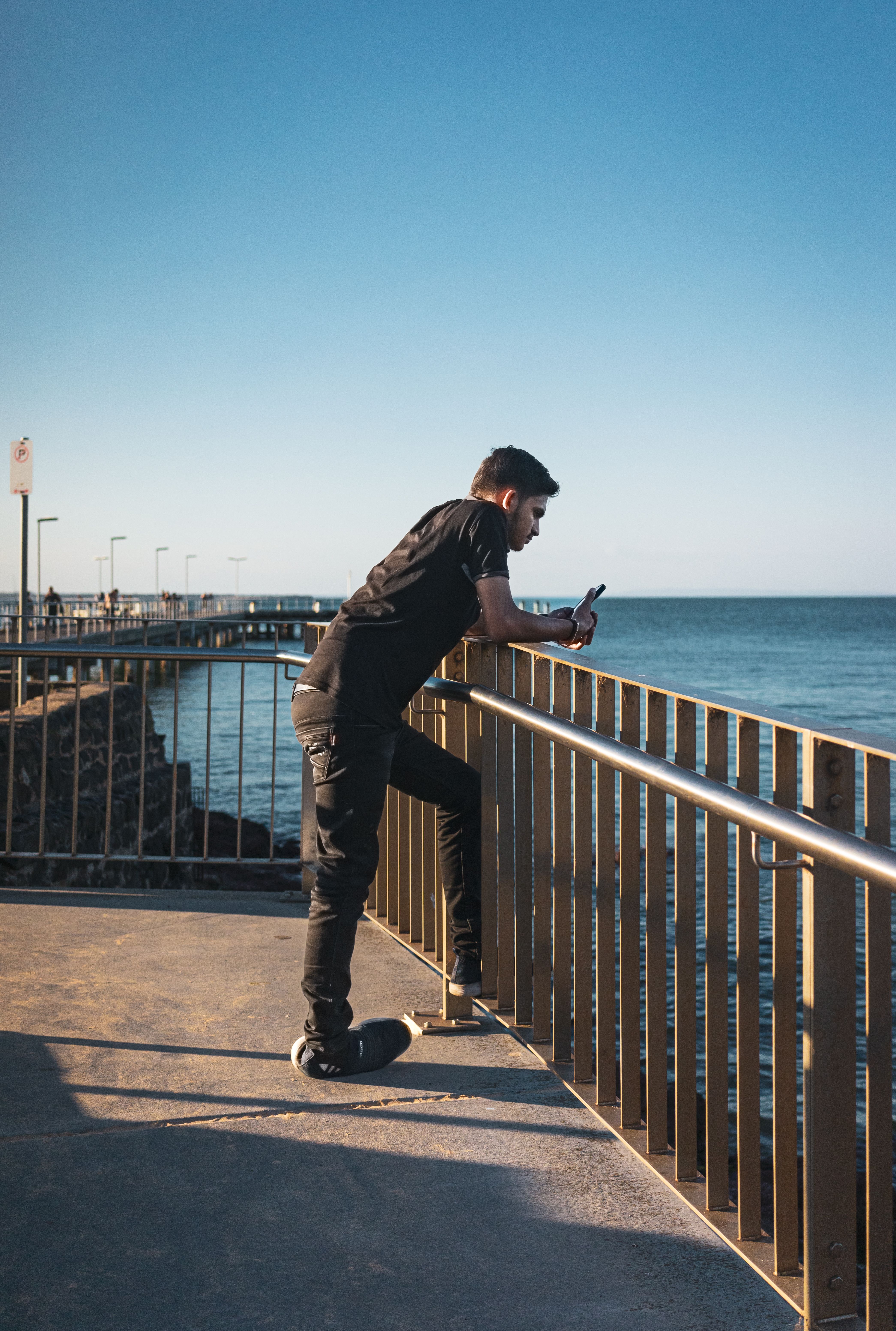 A man standing on a railing looking at the ocean · Free Stock Photo