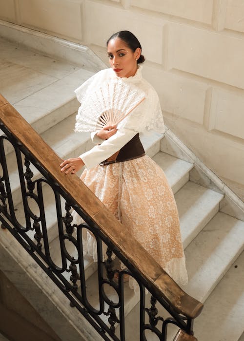 A woman in a skirt and white blouse is standing on some stairs