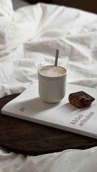 Cup of coffee and chocolate bar on a book, creating a cozy morning vibe.
