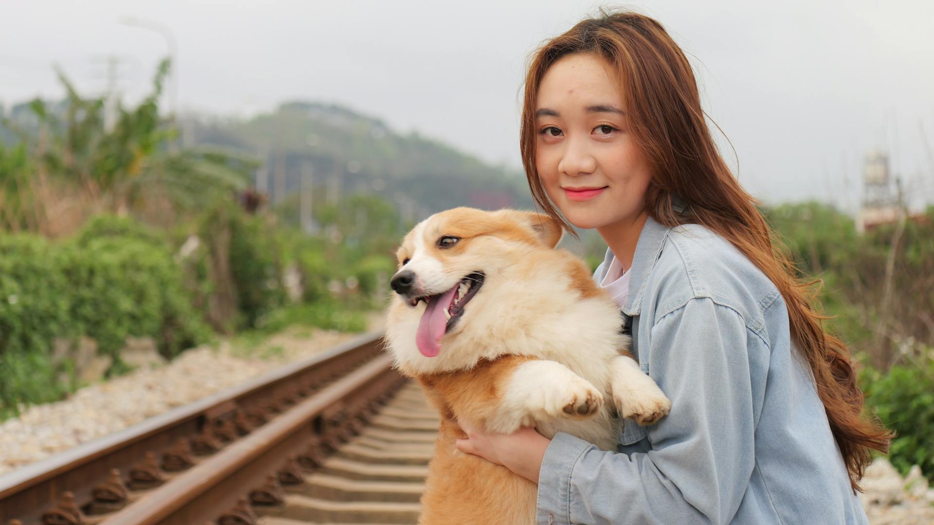 En ung kvinna håller och kramar sin corgihund